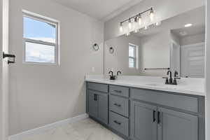 Bathroom with double vanity and light marble finish flooring