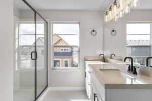 Bathroom with double vanity, a shower stall, and light tile patterned flooring