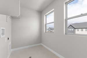 Laundry room with hookup for an electric dryer, light tile patterned flooring, and hookup for a washing machine