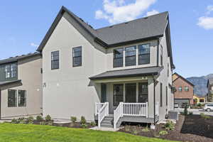 View of front of home featuring a porch, stucco siding, a mountain view, roof with shingles, and a front yard