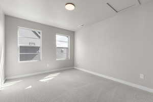 Empty room featuring carpet flooring, a textured ceiling, and attic access