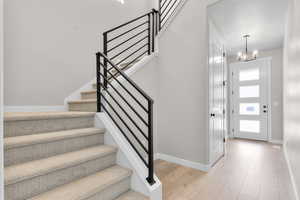 Foyer with light wood-type flooring, a chandelier, stairway, and a textured ceiling