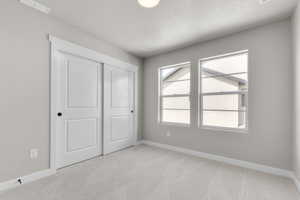 Unfurnished bedroom with carpet flooring, a textured ceiling, and a closet