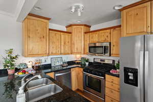 Kitchen with granite counters, stainless steel appliances, gas range and custom cabinets.