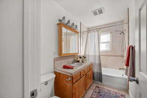 Main bath with shower / tub combo with curtain, vanity, and light tile patterned floors.