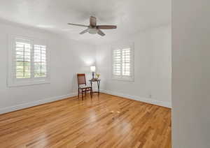 Primary bedroom with hardwoods and a ceiling fan.