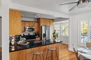 Kitchen with stainless steel appliances, crown molding and windows looking out to the backyard.