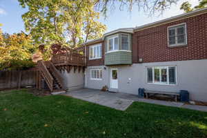 Back of property featuring stirs down from the deck to a patio area and door from lower level out to backyard