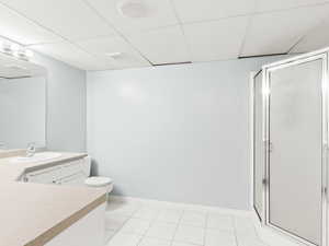 Bathroom with a stall shower, vanity, a paneled ceiling, and light tile patterned floors