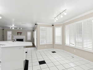 Kitchen with track lighting, light tile patterned floors, light countertops, a center island with sink, and open floor plan