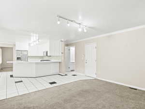 Kitchen with light tile patterned flooring, track lighting, open floor plan, a peninsula, and light carpet