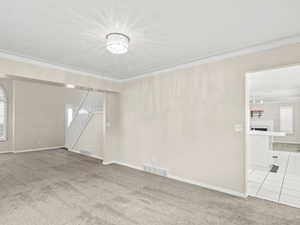 Unfurnished room with light carpet, ornamental molding, stairs, a fireplace, and light tile patterned flooring
