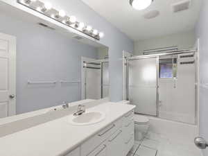 Bathroom with enclosed tub / shower combo, vanity, and light tile patterned floors