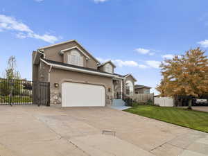 View of front facade featuring stucco siding, concrete driveway, stone siding, and a garage
