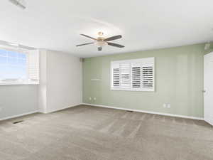 Spare room featuring light carpet, healthy amount of natural light, and ceiling fan