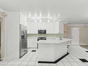 Kitchen featuring ornamental molding, a peninsula, white cabinetry, light countertops, and stainless steel appliances