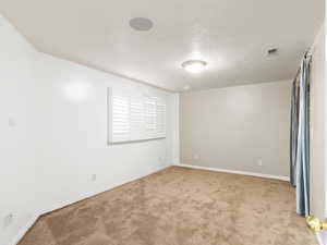 Empty room featuring a textured ceiling and light colored carpet