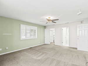 Unfurnished bedroom featuring carpet floors, a spacious closet, connected bathroom, and a ceiling fan