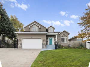 Traditional-style home with stone siding, concrete driveway, an attached garage, stucco siding, and a gate