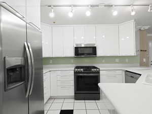 Kitchen featuring appliances with stainless steel finishes, white cabinets, and light tile patterned floors