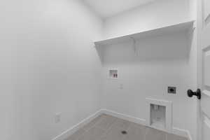 Laundry area featuring hookup for a washing machine, electric dryer hookup, and light tile patterned floors