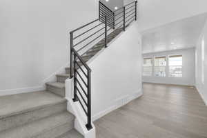 Stairs with wood finished floors and recessed lighting