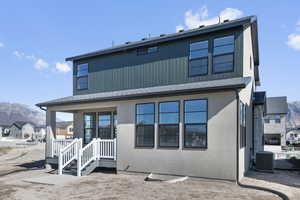 Back of property with a mountain view, a shingled roof, and stucco siding