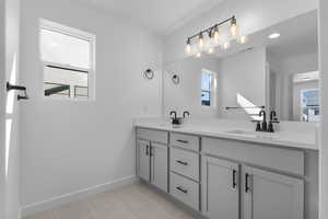 Full bathroom with double vanity, light tile patterned floors, and healthy amount of natural light