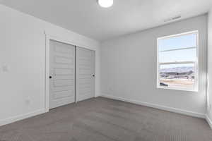Unfurnished bedroom with carpet flooring, a closet, a mountain view, and a textured ceiling