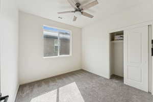Bedroom featuring light colored carpet, ceiling fan, and a closet