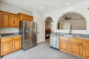 Kitchen featuring light stone countertops, stainless steel appliances, brown cabinetry, and recessed lighting