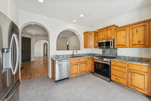 Kitchen featuring light stone counters, appliances with stainless steel finishes, light tile patterned floors, recessed lighting, and brown cabinets