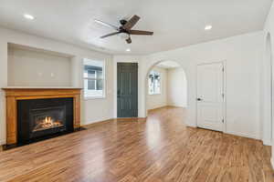 Living room with plenty of natural light, light wood finished floors, recessed lighting, and arched walkways