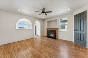 Living room with a fireplace with flush hearth, wood finished floors, healthy amount of natural light, and recessed lighting
