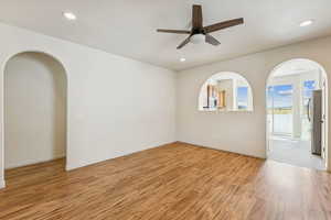 Living room featuring arched walkways, light wood-style flooring, recessed lighting, and ceiling fan