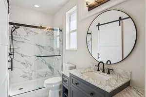 Primary bathroom with a marble finish shower and vanity