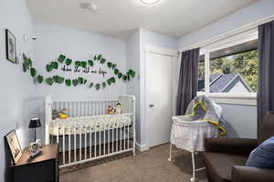 Carpeted bedroom with a crib and baseboards