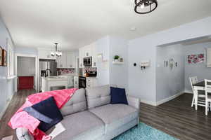 Living area featuring a chandelier and dark wood-style flooring