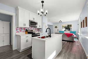 Kitchen with appliances with stainless steel finishes, white cabinetry, a kitchen island with sink, and open floor plan