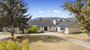 Ranch-style home with brick siding, a mountain view, a front lawn, and a shingled roof