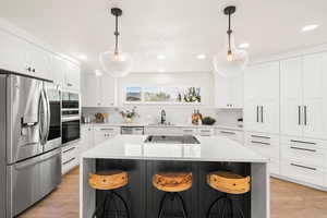 Kitchen featuring black appliances, a breakfast bar area, hanging light fixtures, a center island, and recessed lighting