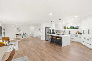 Kitchen featuring white cabinetry, a kitchen bar, a center island, and recessed lighting