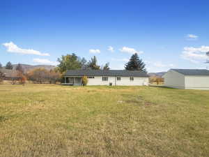 Back of house with a mountain view and a lawn
