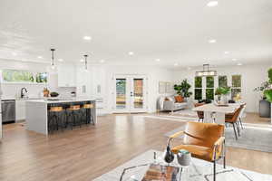 Living room featuring french doors, healthy amount of natural light, recessed lighting, and light wood finished floors