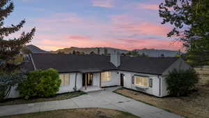 View of front of house featuring brick siding, a mountain view, driveway, a shingled roof, and a chimney