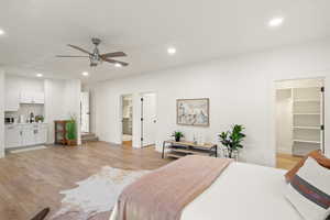 Bedroom with a walk in closet, light wood-type flooring, recessed lighting, and a ceiling fan