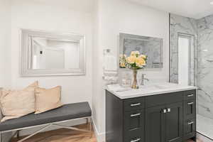 Bathroom with vanity, a marble finish shower, and light wood-type flooring