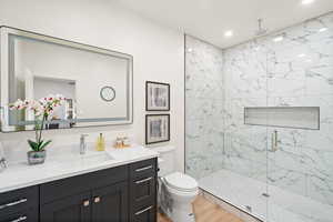 Bathroom featuring a marble finish shower, vanity, light wood finished floors, and recessed lighting