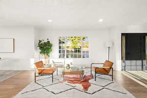 Living area featuring wood finished floors, a textured ceiling, and recessed lighting