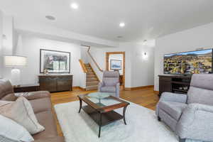Living room featuring wood finished floors, stairway, and recessed lighting